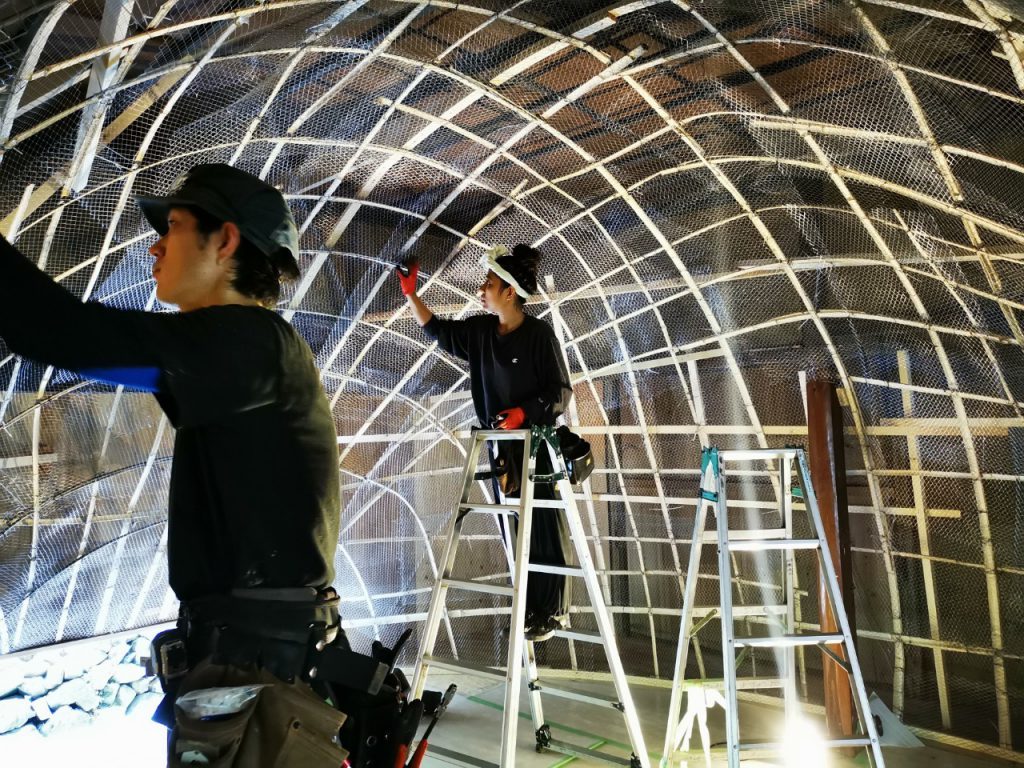 Two persons are working on a  metallic structure